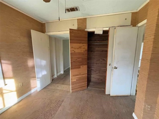 unfurnished bedroom featuring a closet and wooden walls