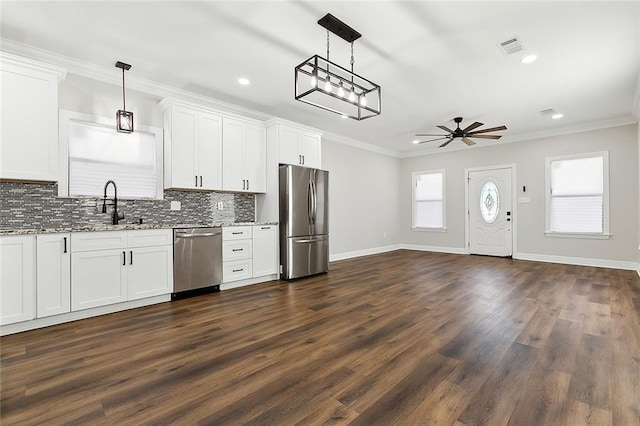 kitchen with appliances with stainless steel finishes, white cabinets, and decorative light fixtures