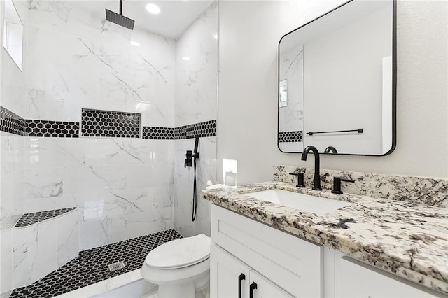 bathroom featuring a tile shower, vanity, and toilet