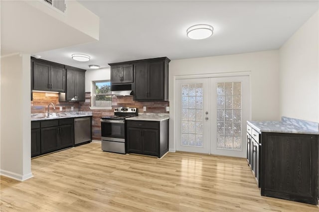 kitchen featuring sink, french doors, light hardwood / wood-style flooring, decorative backsplash, and appliances with stainless steel finishes