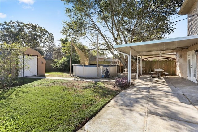 view of yard with a storage shed, a fenced in pool, ceiling fan, and a patio area