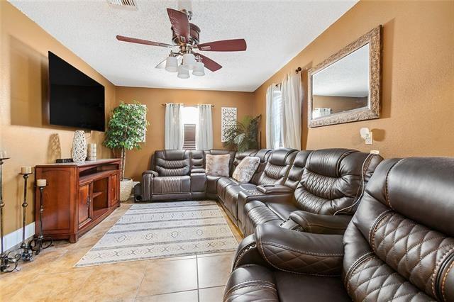 tiled living room with ceiling fan and a textured ceiling