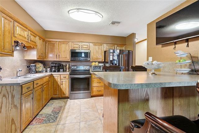 kitchen with kitchen peninsula, a textured ceiling, stainless steel appliances, and sink