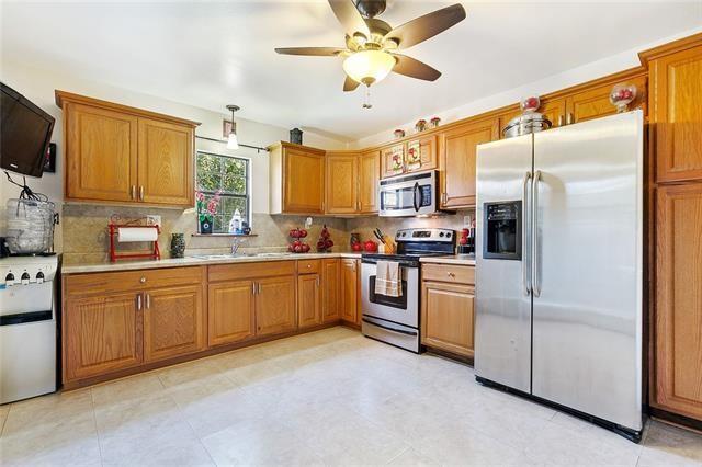 kitchen with ceiling fan, sink, hanging light fixtures, stainless steel appliances, and decorative backsplash