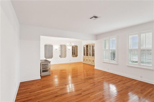 unfurnished living room featuring hardwood / wood-style floors and an inviting chandelier