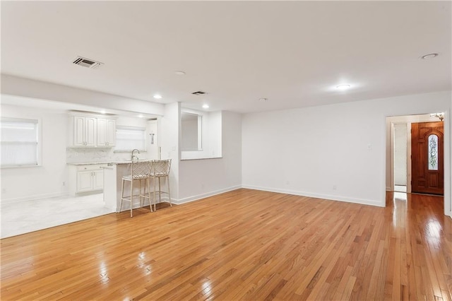 unfurnished living room featuring sink and light hardwood / wood-style floors