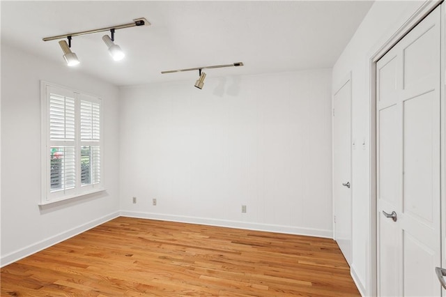 unfurnished bedroom featuring rail lighting and light hardwood / wood-style floors