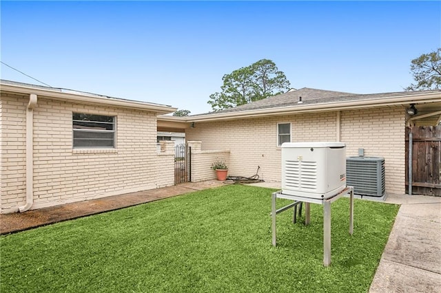 back of property with central AC unit and a lawn