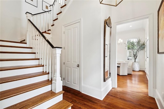 staircase with hardwood / wood-style flooring and ornamental molding