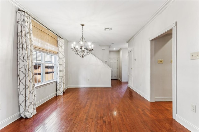 unfurnished dining area with dark wood-type flooring, crown molding, and an inviting chandelier