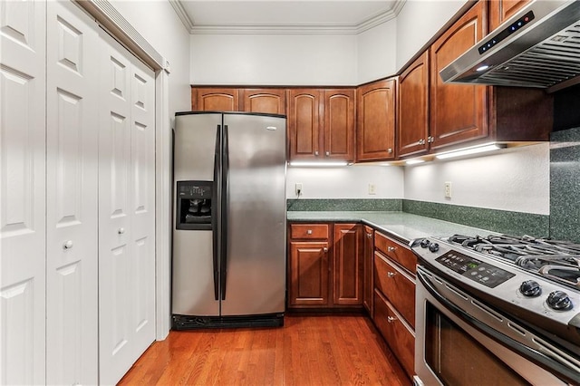 kitchen featuring dark wood-type flooring, stainless steel appliances, extractor fan, and crown molding