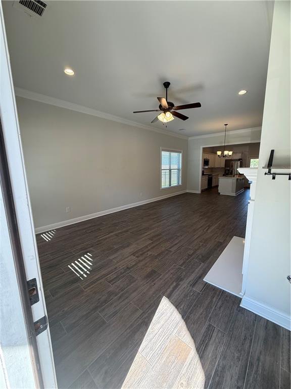 unfurnished living room with ceiling fan, ornamental molding, and dark hardwood / wood-style flooring