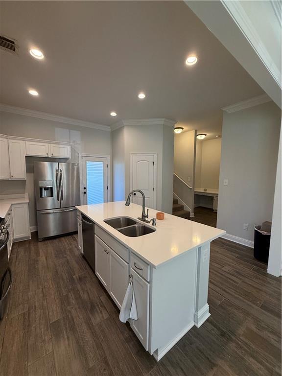 kitchen with sink, a kitchen island with sink, white cabinetry, and stainless steel appliances