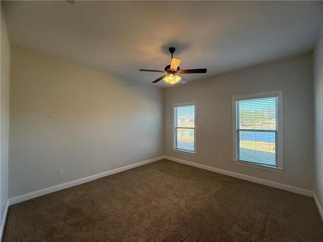 spare room featuring ceiling fan and dark colored carpet