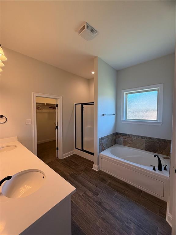 bathroom featuring plus walk in shower, vanity, hardwood / wood-style floors, and vaulted ceiling