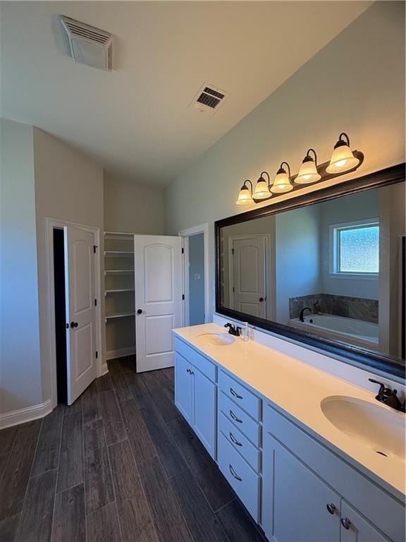 bathroom with a tub, vanity, and wood-type flooring