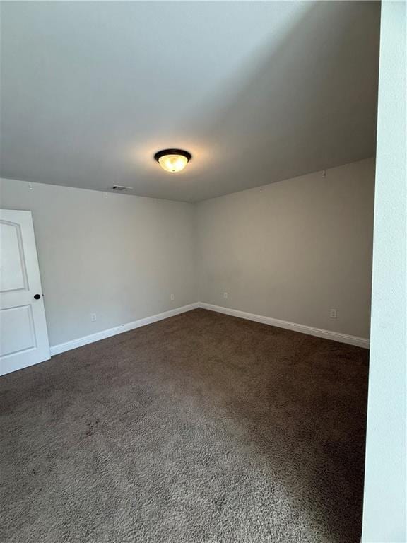 unfurnished room featuring dark carpet