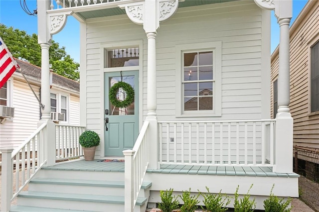 view of exterior entry featuring cooling unit and covered porch