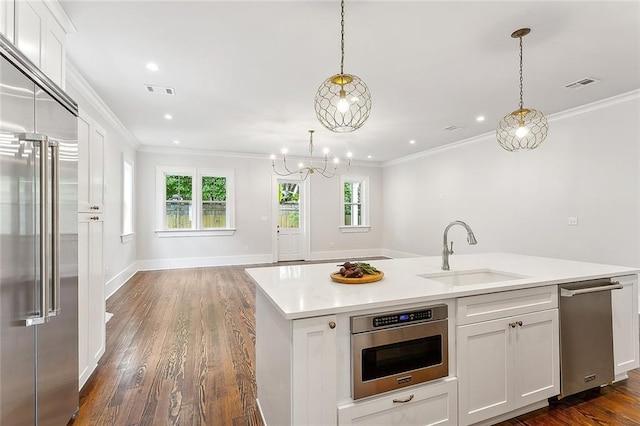 kitchen featuring sink, an island with sink, decorative light fixtures, white cabinets, and appliances with stainless steel finishes