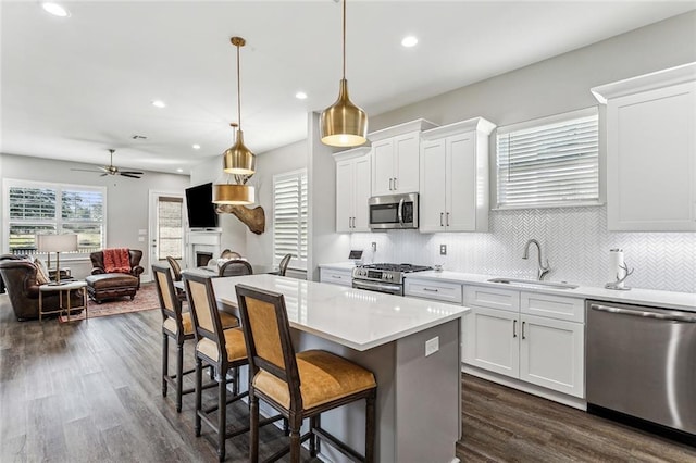 kitchen featuring sink, white cabinets, stainless steel appliances, and decorative light fixtures