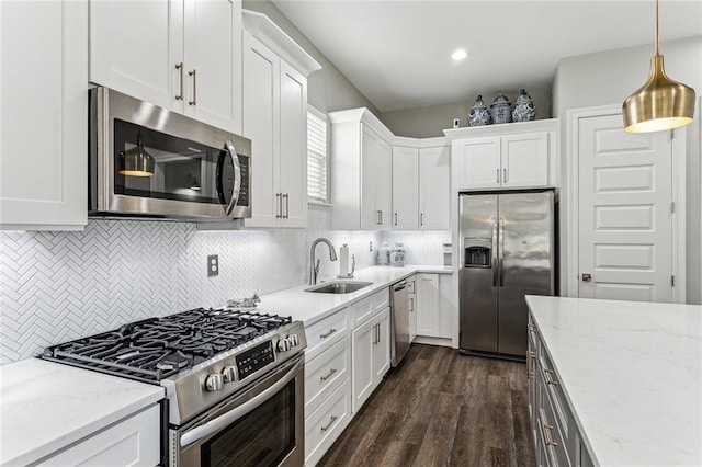 kitchen featuring white cabinetry, sink, stainless steel appliances, and decorative light fixtures