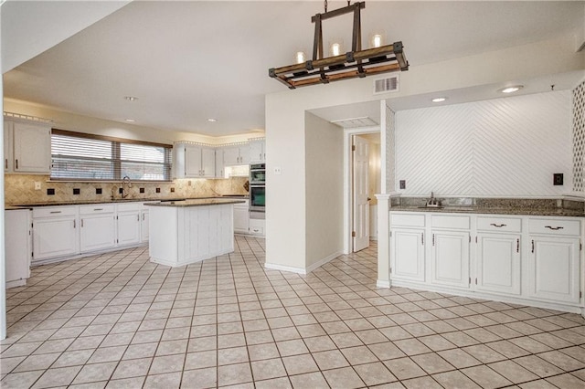 kitchen with sink, white cabinetry, tasteful backsplash, double oven, and pendant lighting