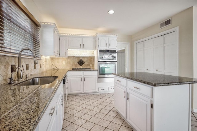 kitchen featuring sink, white cabinets, double oven, and dark stone counters