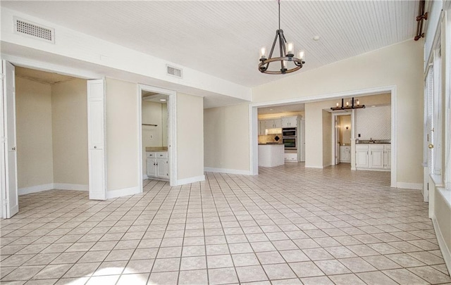 unfurnished living room featuring light tile patterned flooring, lofted ceiling, sink, and a chandelier