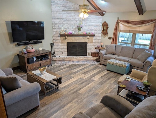 living room with hardwood / wood-style flooring, ceiling fan, vaulted ceiling with beams, and a fireplace