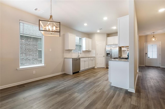 kitchen featuring white cabinets, dark hardwood / wood-style flooring, stainless steel appliances, and hanging light fixtures