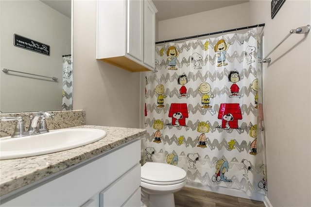 bathroom with hardwood / wood-style floors, vanity, curtained shower, and toilet