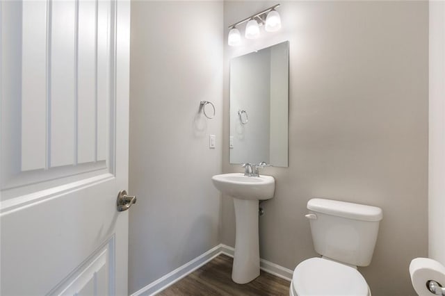 bathroom with toilet, wood-type flooring, and sink