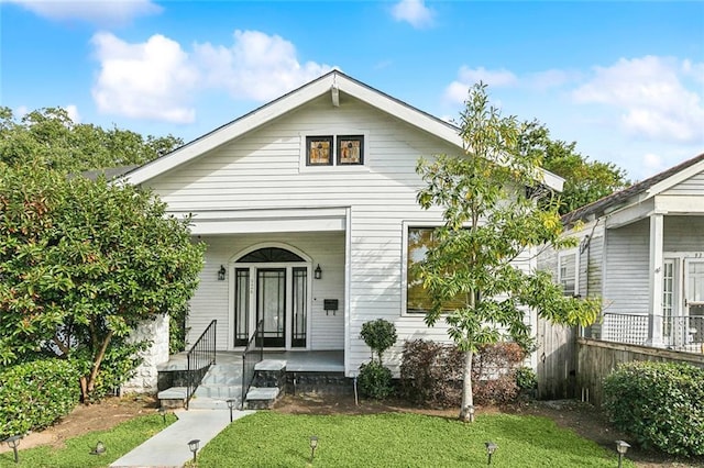 bungalow-style home featuring covered porch and a front lawn