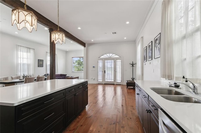 kitchen featuring sink, beamed ceiling, stainless steel dishwasher, a notable chandelier, and pendant lighting