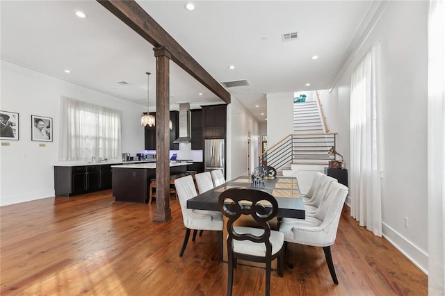 dining area featuring hardwood / wood-style flooring, ornamental molding, sink, and an inviting chandelier