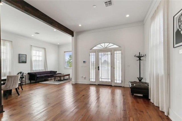 foyer entrance with beamed ceiling, wood-type flooring, and crown molding