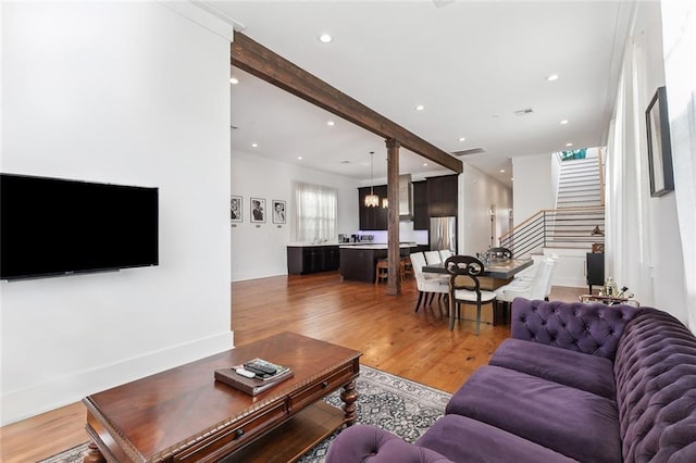 living room featuring hardwood / wood-style floors, beamed ceiling, and an inviting chandelier