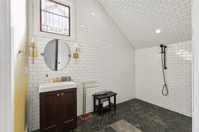 bathroom featuring vanity, a shower, tile walls, and vaulted ceiling