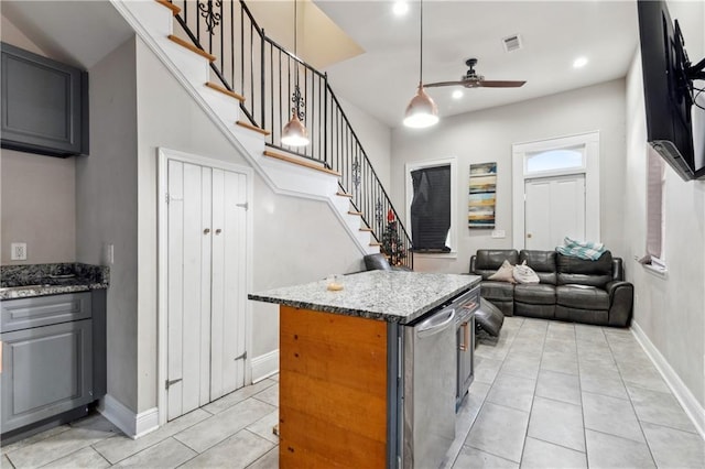 kitchen with dark stone counters, ceiling fan, pendant lighting, light tile patterned floors, and a kitchen island