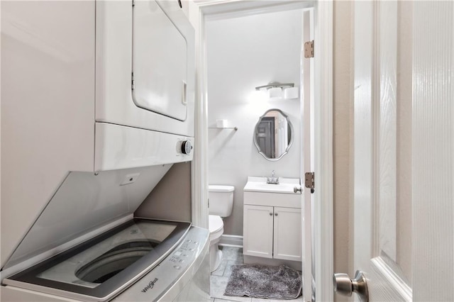 bathroom featuring tile patterned floors, vanity, toilet, and stacked washer / dryer