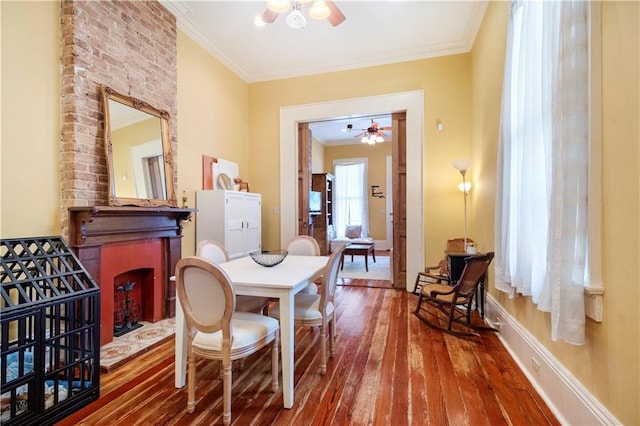 dining space featuring a large fireplace, ornamental molding, and hardwood / wood-style flooring