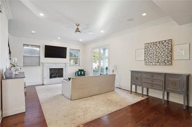 living room with dark hardwood / wood-style floors, ceiling fan, ornamental molding, and a fireplace