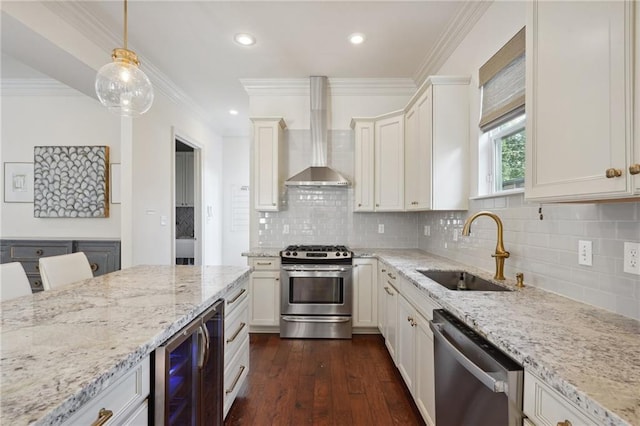 kitchen with sink, wall chimney exhaust hood, stainless steel appliances, wine cooler, and decorative light fixtures