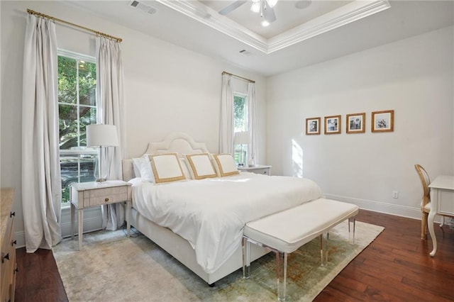 bedroom with multiple windows, a tray ceiling, ceiling fan, and hardwood / wood-style flooring