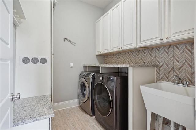 laundry room with cabinets, washer and dryer, and sink