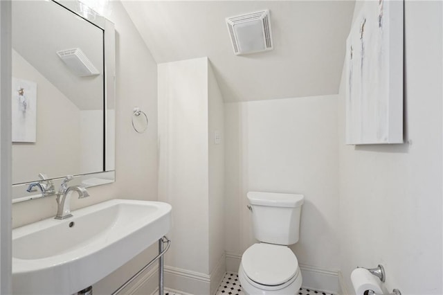 bathroom with toilet, sink, and vaulted ceiling