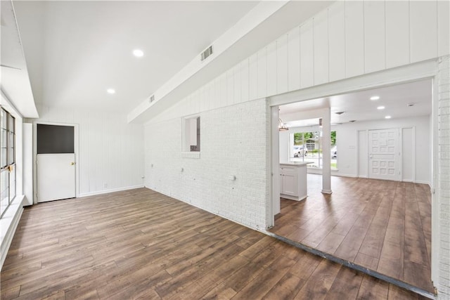 309 W Joan St, Gonzales, LA 70737 - unfurnished living room with dark wood-type flooring and brick wall