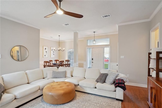 living room with crown molding, wood-type flooring, and ceiling fan with notable chandelier