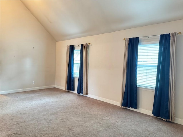 spare room with carpet floors, a healthy amount of sunlight, and lofted ceiling