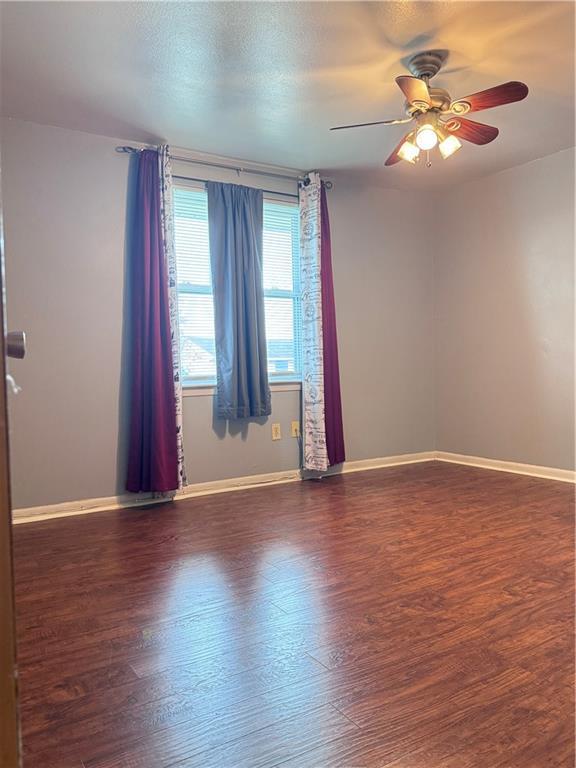 unfurnished room with ceiling fan and dark hardwood / wood-style flooring